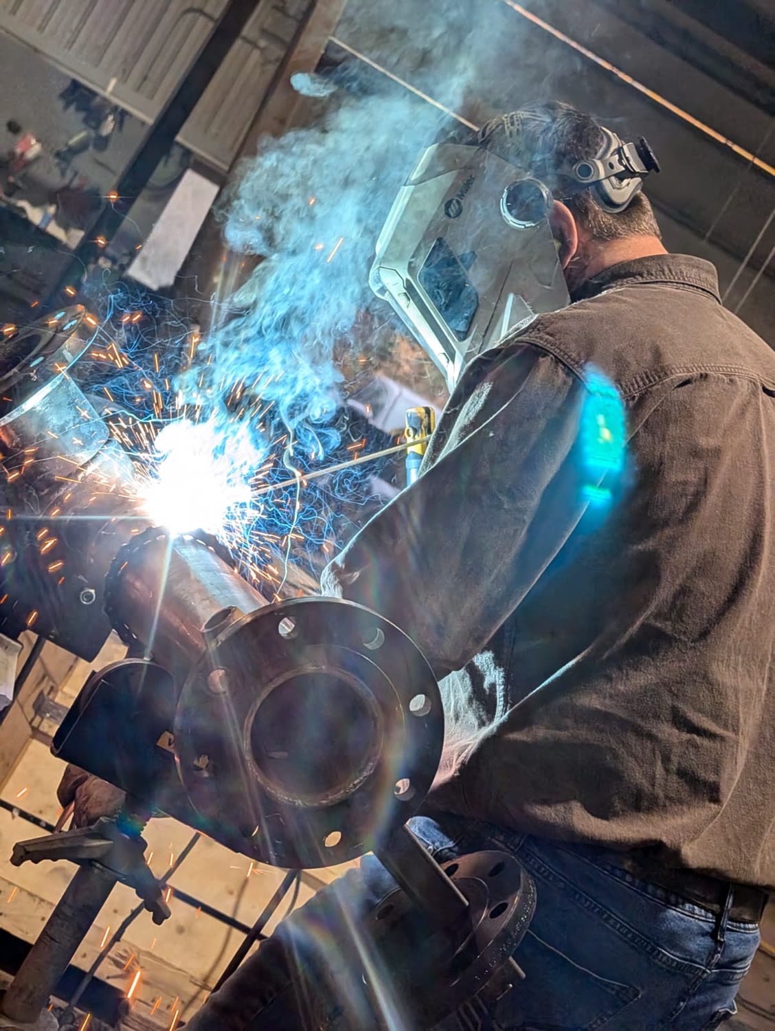 Sparks flying while welding a pipe spool in the fabrication shop